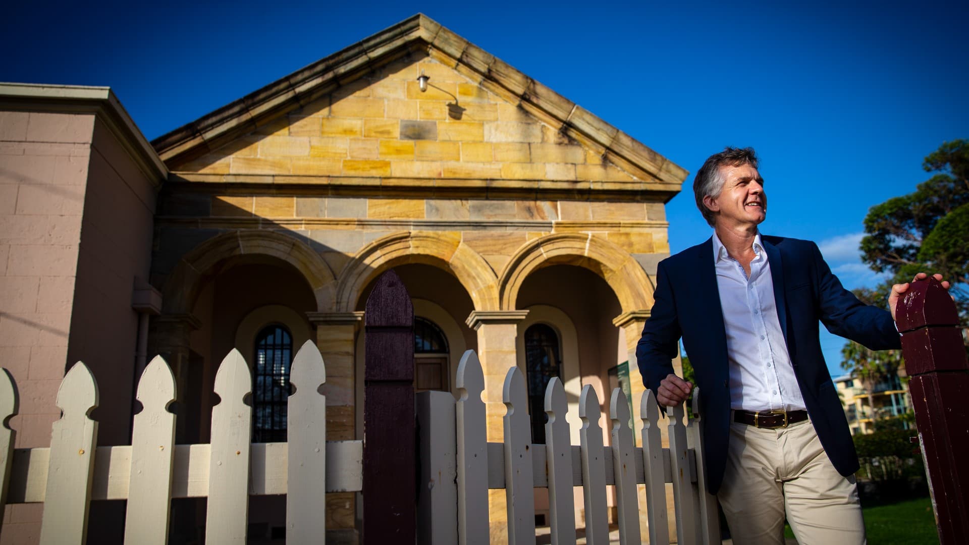 Associate Professor Nicholas Gill leans on a white fence in front of Wollongong Courthouse. Photo: Paul Jones