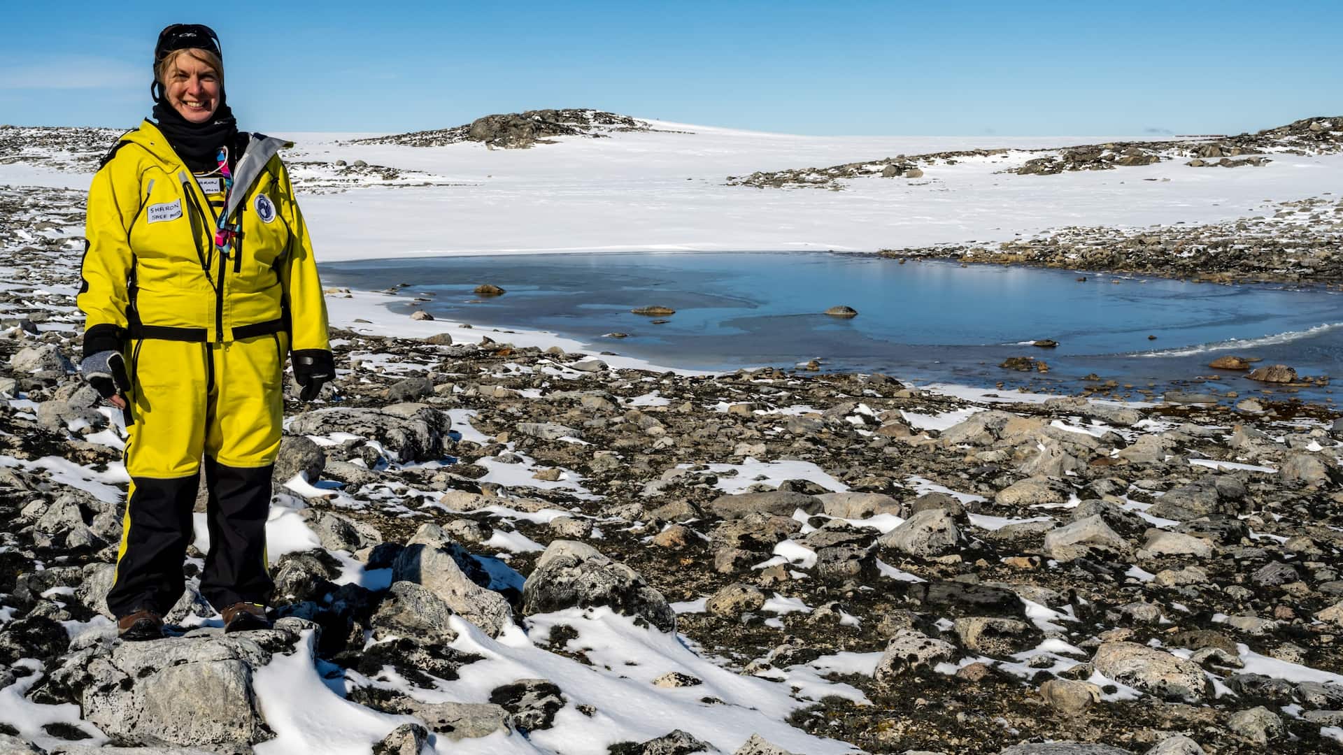 Sharon Robinson wears a yellow snow suit as she stands in the snow of Antarctica. Photo: Supplied