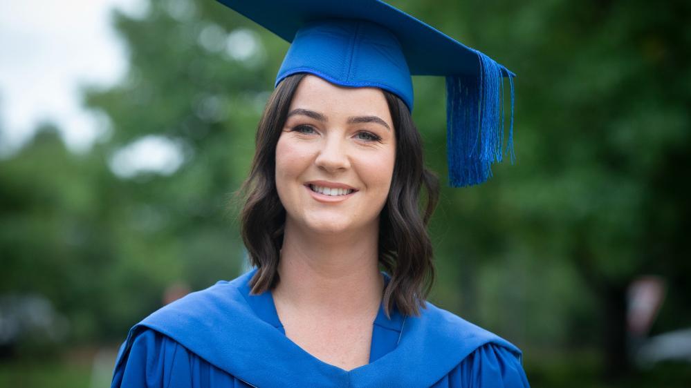 UOW Shoalhaven graduate Penelope McMillan, wearing a blue graduation gown and cap. Photo: Paul Jones