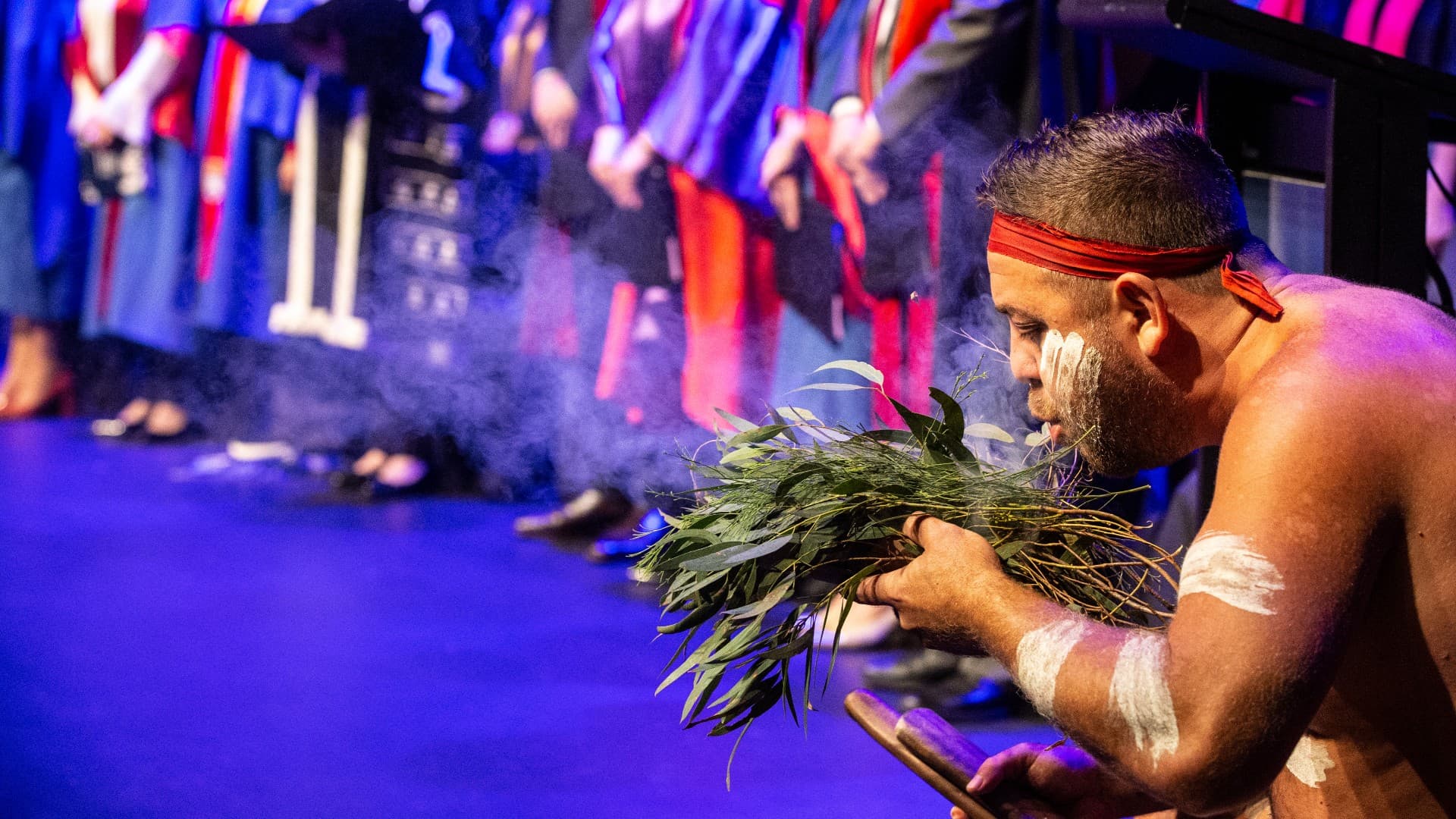 An Aboriginal Elders blows on a handful of leaves during a smoking ceremony for the Shoalhaven graduations. Photo: Paul Jones