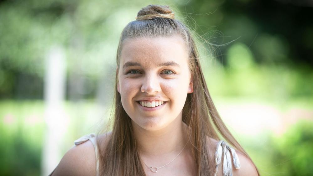 A close up shot of Carly Lavings. She smiles at the camera, has a silver necklace and her hair in a bun. Photo: Paul Jones