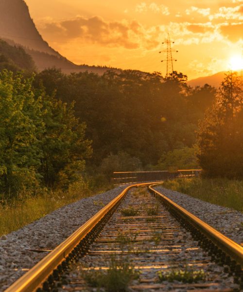 Train tracks at sunrise with hills and trees in the distance
