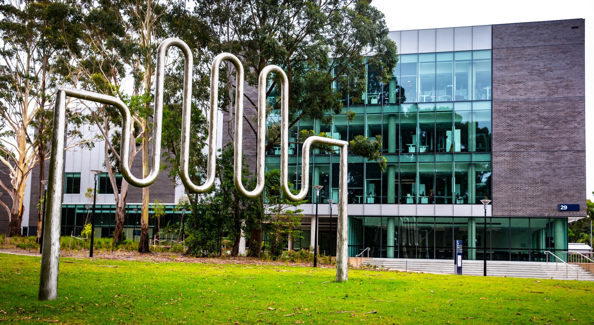 An image of a sculpture in the foreground, with the Jillian Broadbent Building in the background, on UOW's Wollongong campus. Photo: Paul Jones