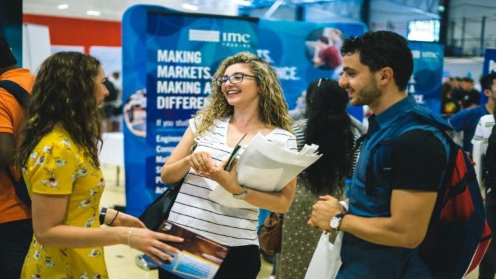 Three people talking at a stall during the UOW Graduate Careers Expo