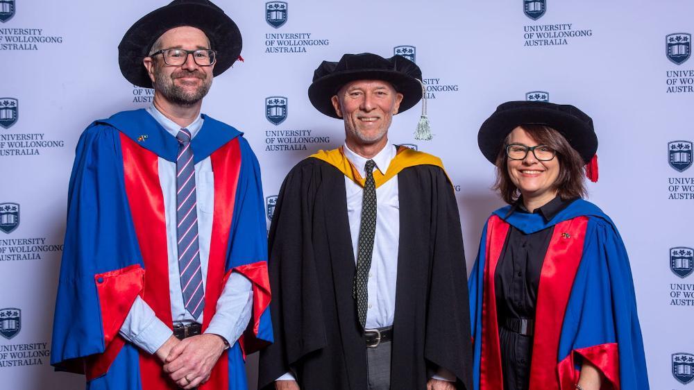 Professor Peter Kelly, Professor Frank Deane and Professor Sue Bennett stand in front of a UOW media wall. Photo: Andy Zakeli