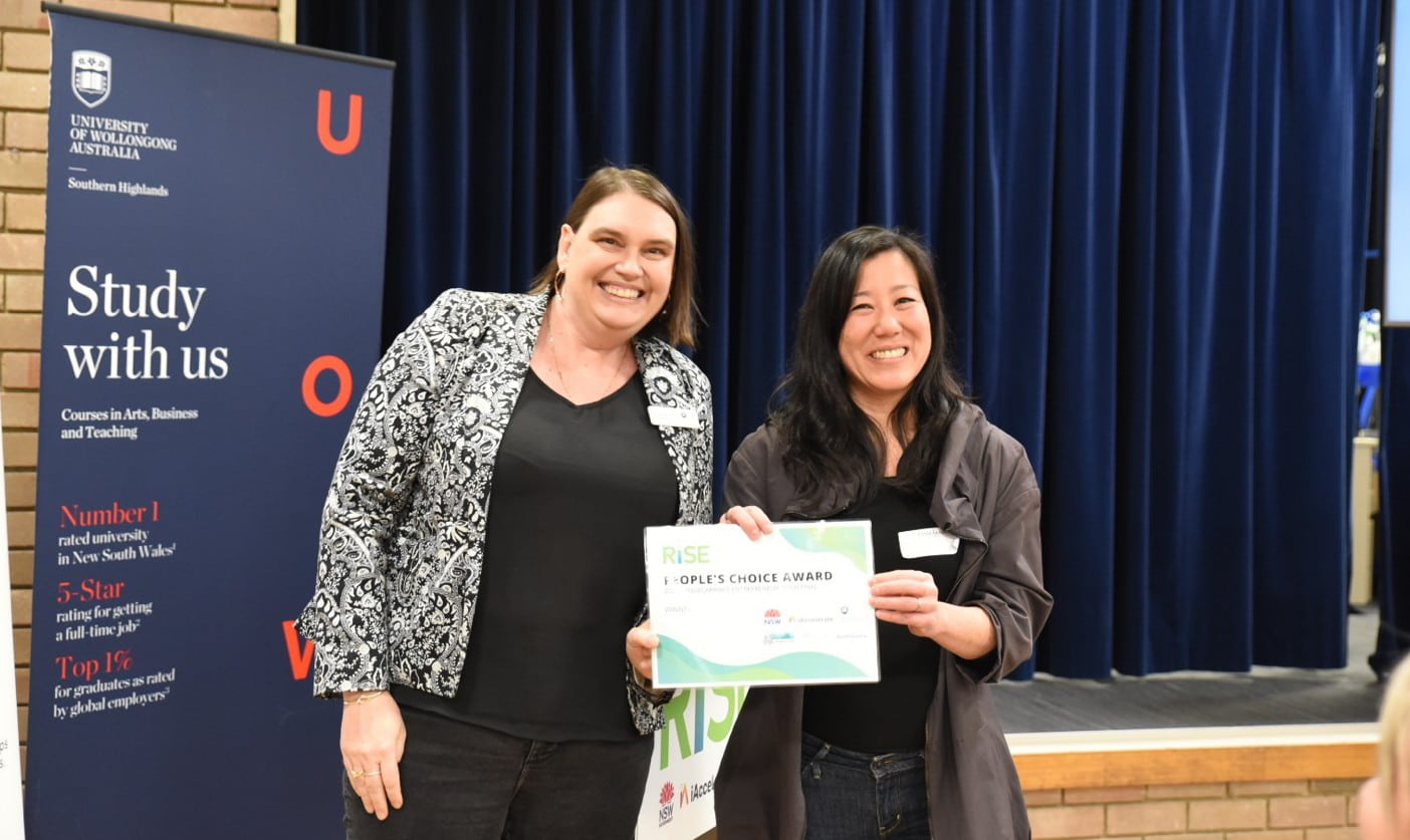 UOW iAccelerate Director Dr Tamantha Stutchbury gives a People's Choice Winner Award to one of the program participants. They are both smiling.