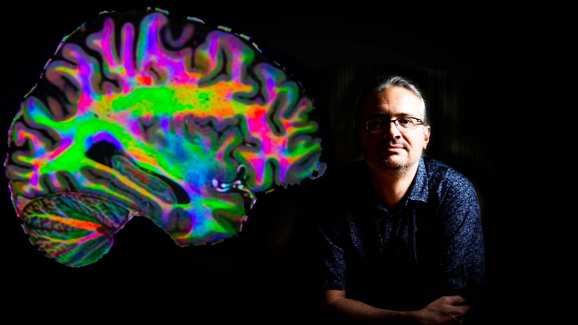 Dr Mark Schira next to a large scan of a brain cross section