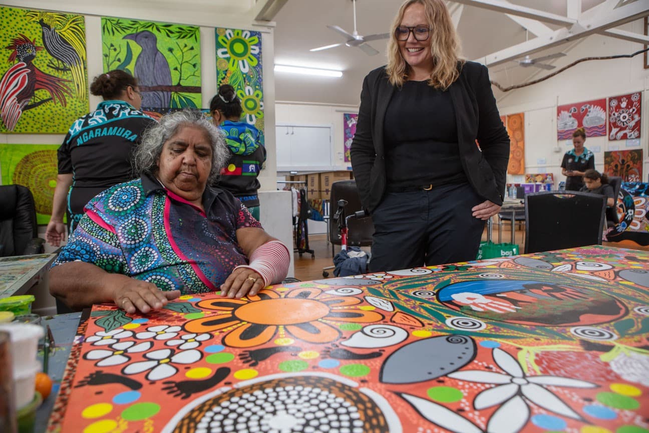Jaymee Beveridge from UOW with the artists behind Cultural Healing. The vibrant painting is in the forefront of the image.