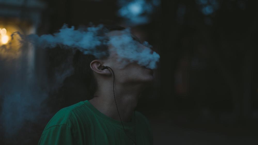 An image of a boy blowing vape smoke out of his mouth. Photo: Tbel Abuseridze, Unsplash
