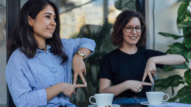 Two women having coffee learning sign language