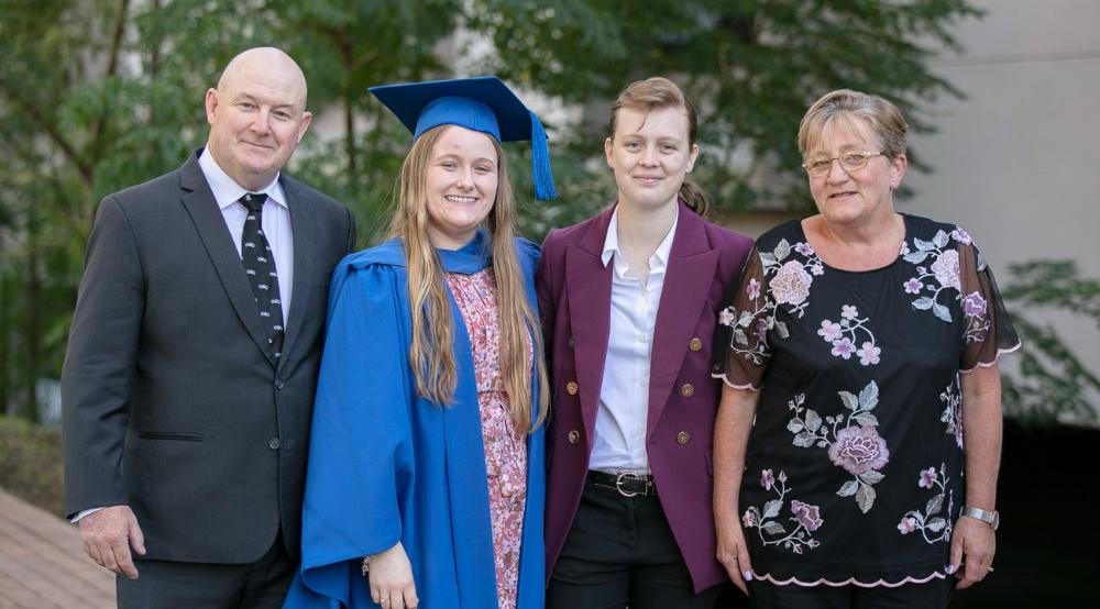 UOW graduate Katana Murphy, middle, is pictured with her family on graduation day. There are four people in the photo. Photo: Paul Jones