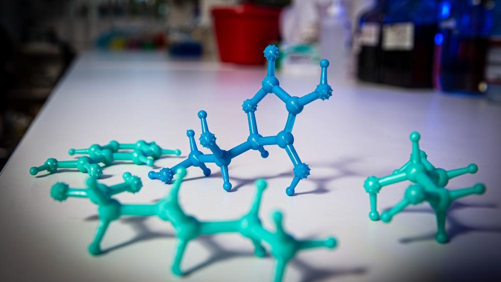 Three examples of the 3D printed chemistry models sit on a laboratory bench. They are coloured blue and green. Photo: Paul Jones