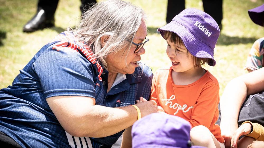 Aunty May with Emily, the young girl who led to the new Aboriginal flag on campus. Emily wears a purple hat and orange shirt. Photo: Paul Jones