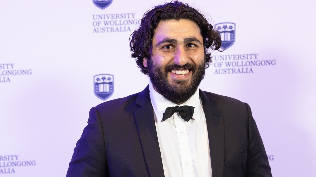 Alumni Award winner Alex Badran holds his award and smiles at the camera. Photo: Mark Newsham