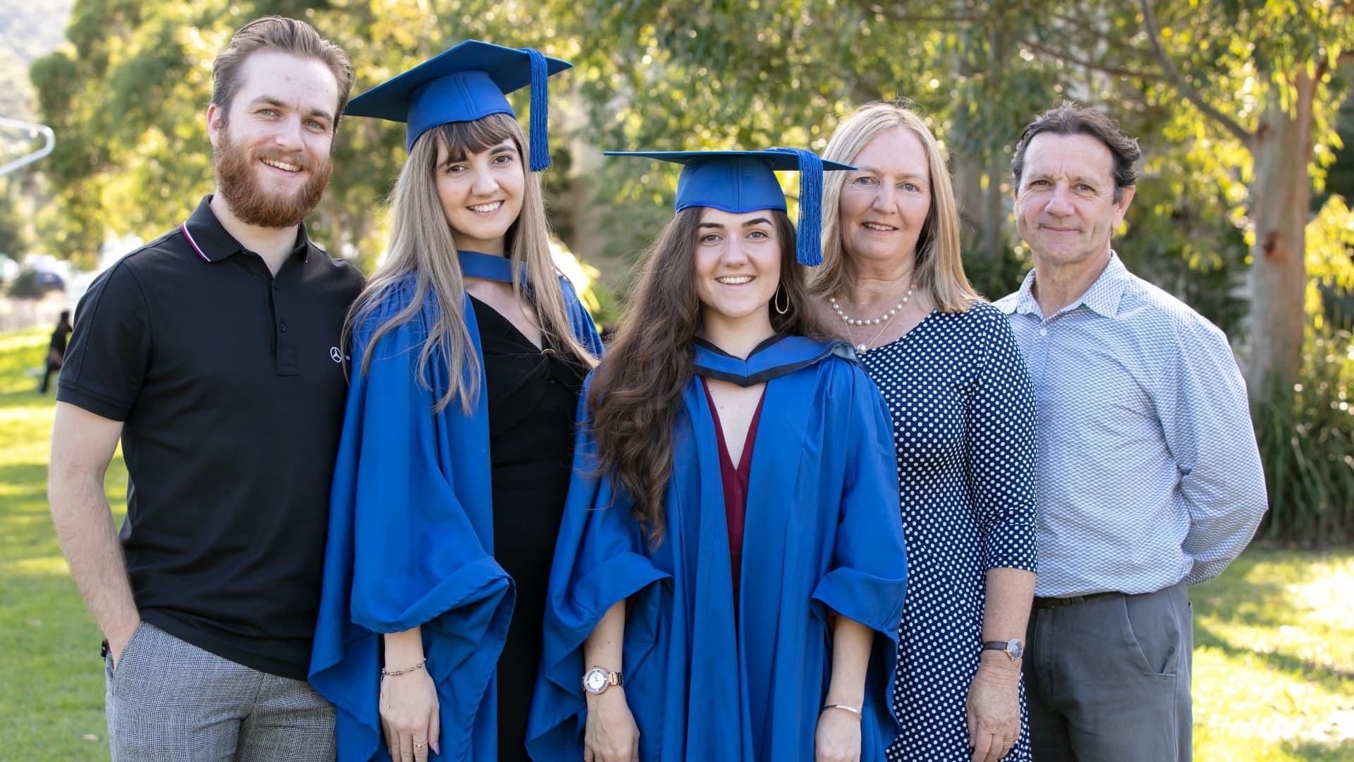 Brenna and Bronte Petrolo, both pictured in their graduation gowns, with their families. Photo: Mark Newsham