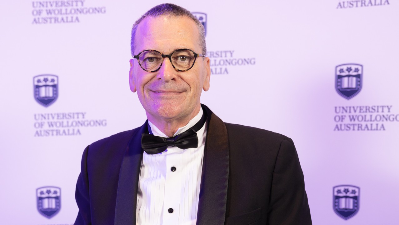 Alumni Award winner Professor John Daly holds his award and smiles at the camera. Photo: Mark Newsham