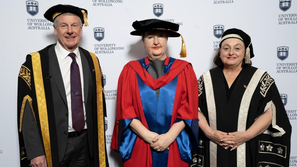 UOW Deputy Chancellor Robert Ryan, Dr Lisa Havilah and UOW Vice-Chancellor Professor Patricia Davidson stand together in front of a UOW wall. Photo: Paul Jones