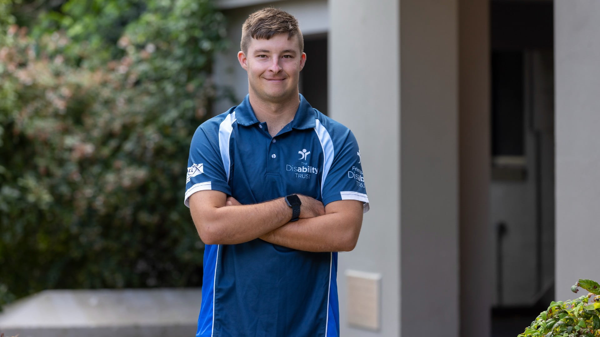 UOW College student Patrick Mitchell wears a blue shirt, with his arms crossed, and smiles at the camera. He is standing in front of a building. Photo: Mark Newsham