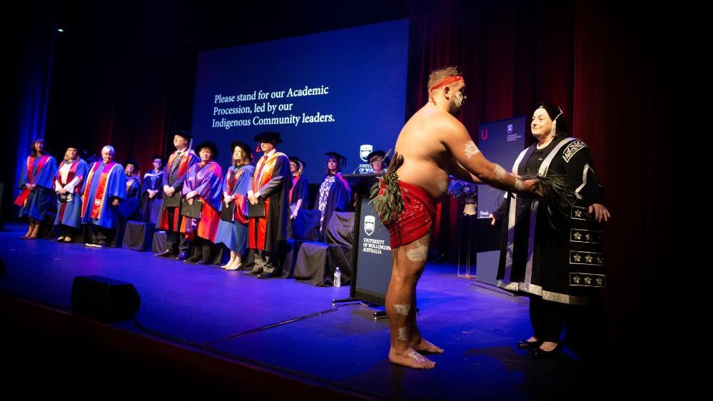 An Aboriginal man performs a smoking ceremony on stage at the UOW Shoalhaven graduations. Photo: Paul Jones