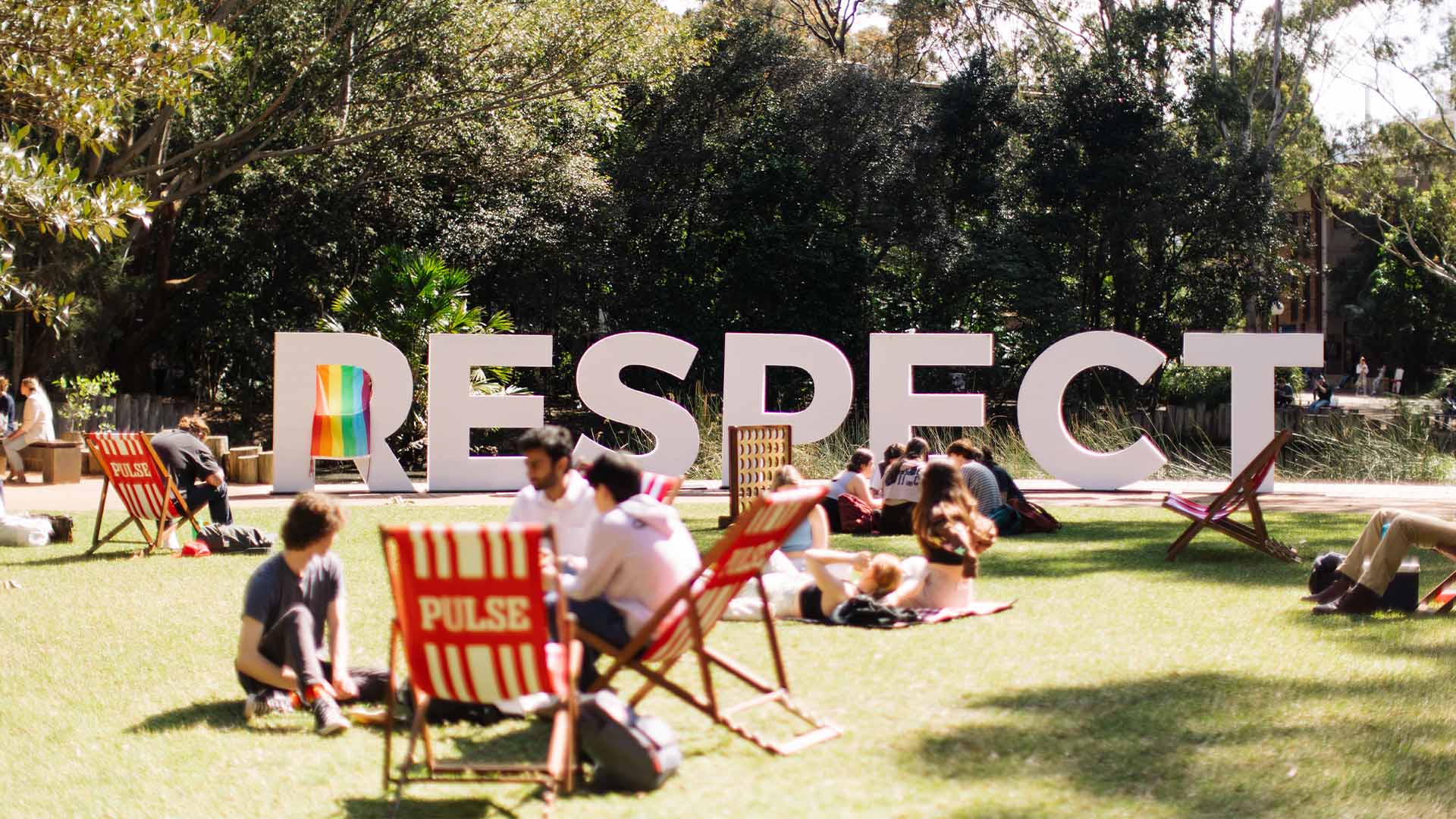 Students sitting on the grass with a sign Respect